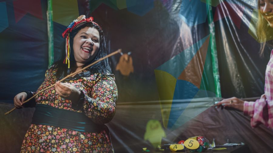 Mulher sorrindo e fazendo pesca em barraca de festa junina.